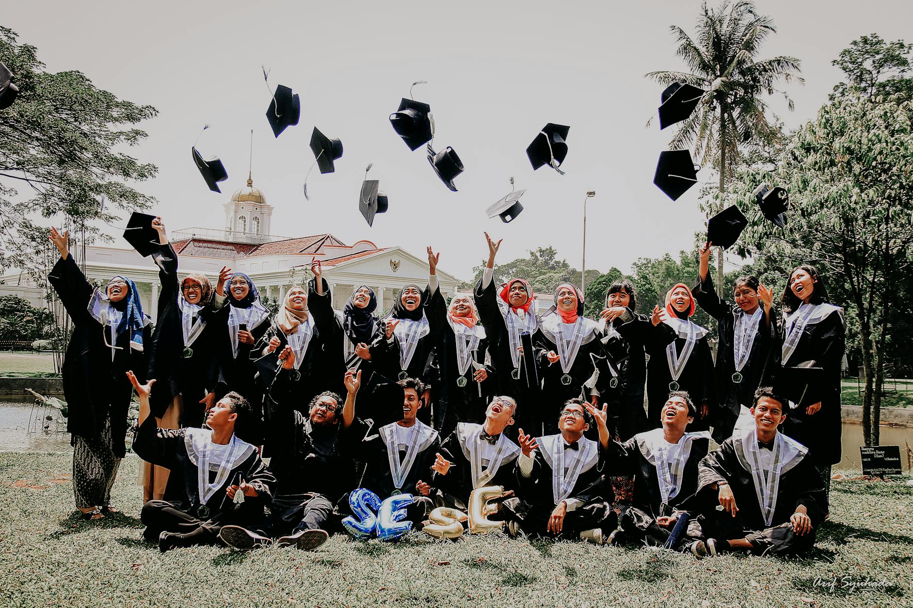 people in blue academic dress sitting on green grass field